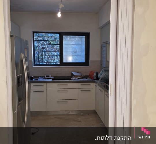 דלת מתקפלת בכניסה למטבח עם מקרר וחלון
